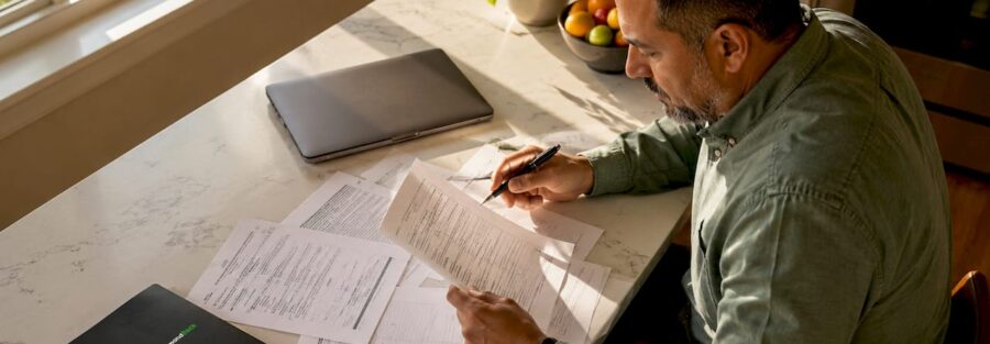 Man reviewing auto insurance policy documents at home