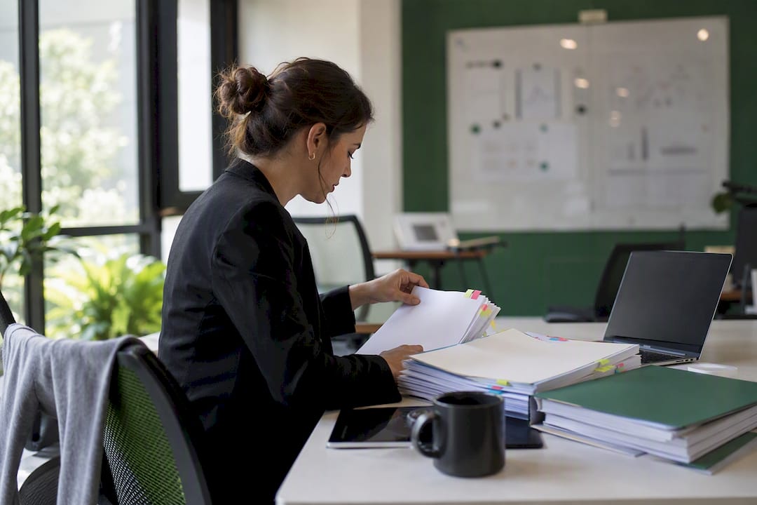 Hands organizing multi-state compliance folders