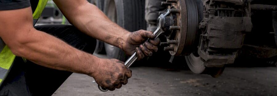 Hands inspecting truck trailer coupling at roadside
