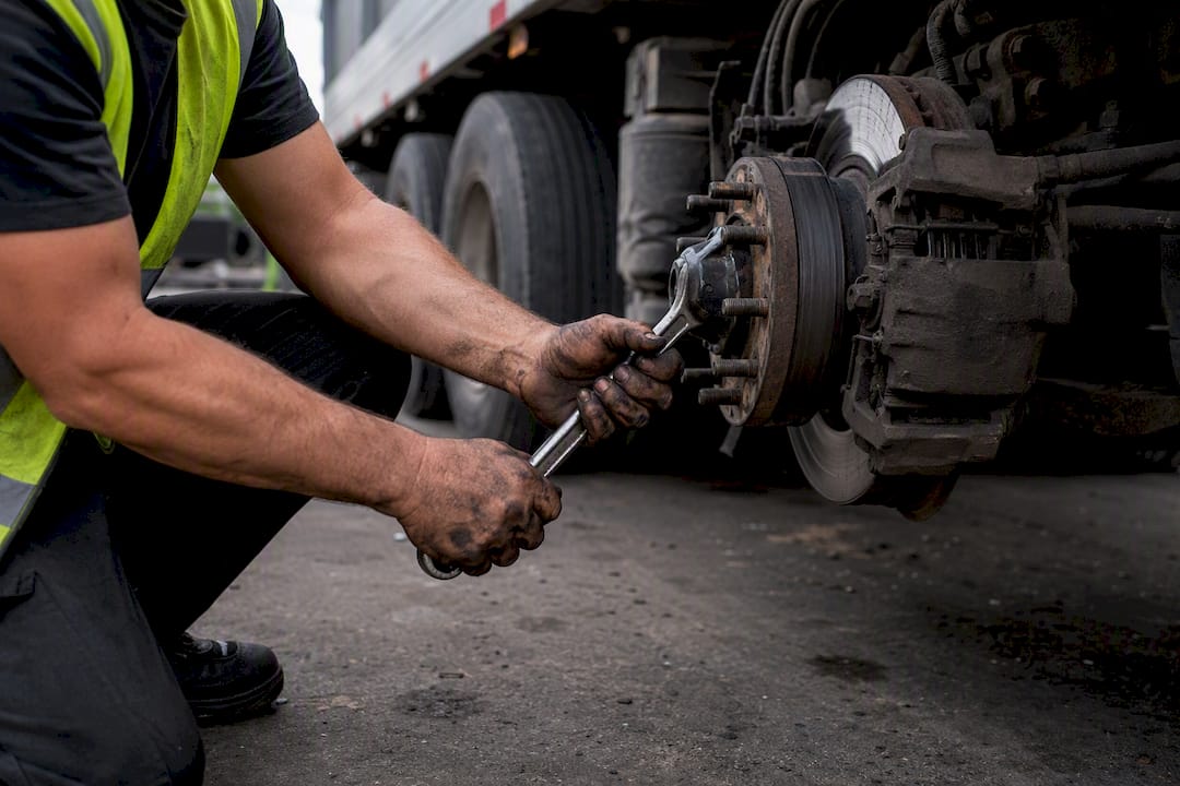 Hands inspecting truck trailer coupling at roadside