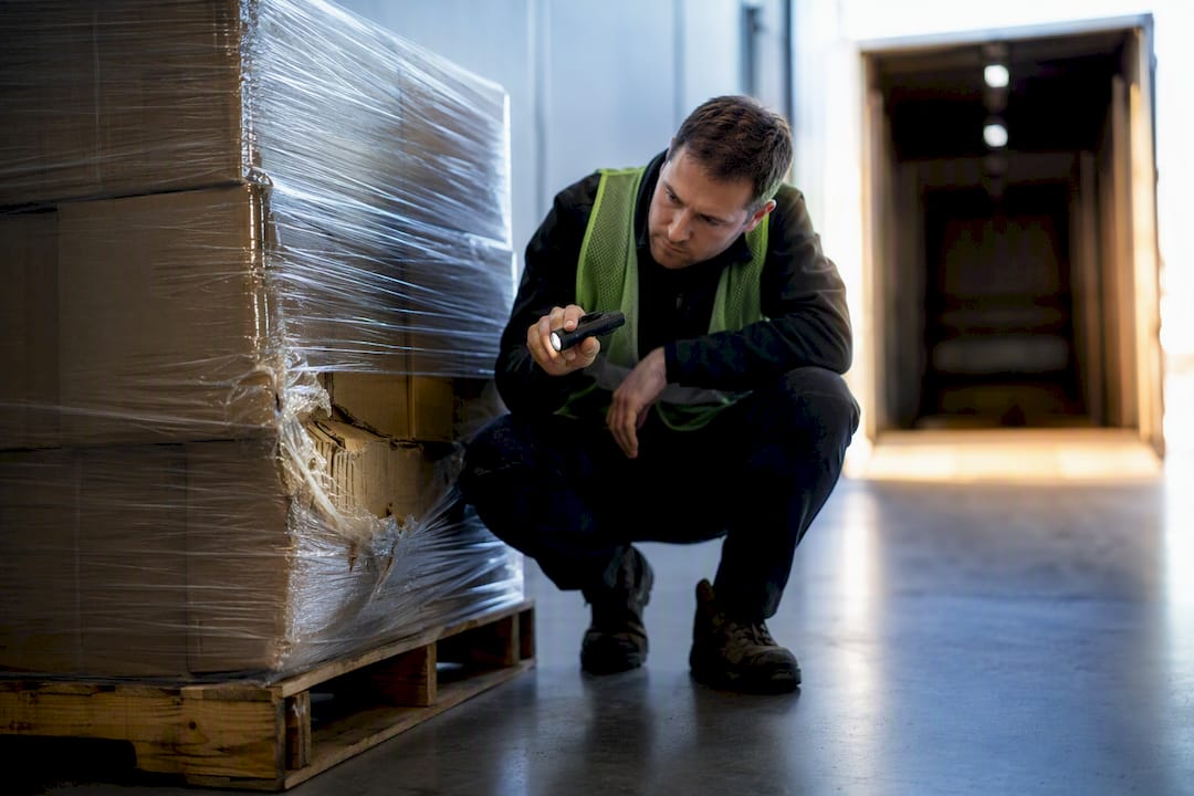 Worker inspecting damaged freight pallet